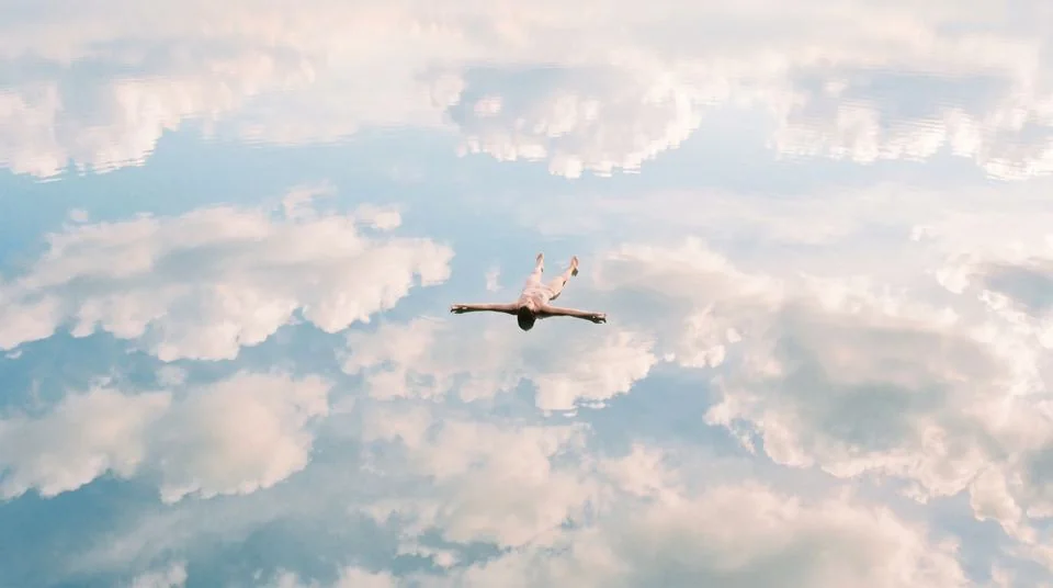 A person floating in a reflection of the sky